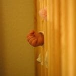 Infant’s Hand Reaching Through Crib Slats – Crib Bumper Lawsuit - Ferraro Law Firm Close-up of a baby’s hand reaching through wooden crib slats, symbolizing safety risks tied to crib bumper products.