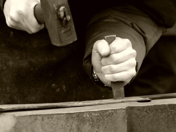 Worker Using Hammer and Chisel – Asbestos Exposure Case - Ferraro Law Firm Close-up of worker’s hands using a hammer and chisel on metal, symbolizing occupational asbestos exposure at industrial worksites.