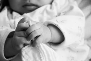 Infant Holding Blanket – Car Seat Recall Safety Risk - Ferraro Law Firm Black and white photo of an infant’s hands clutching a blanket, symbolizing child safety concerns tied to defective car seat recalls.