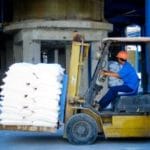Worker Operating Forklift with Industrial Load – Asbestos Industry Case - Ferraro Law Firm Worker in a hard hat driving a forklift carrying stacked industrial bags, symbolizing occupational asbestos exposure and related claims in the Garlock settlement.