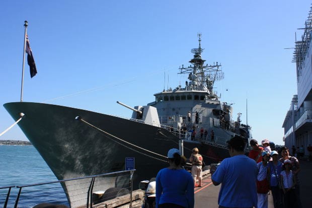 Navy Ship Docked with Visitors – Veteran Asbestos Exposure Case - Ferraro Law Firm Large Navy ship docked at port with visitors walking nearby, representing asbestos exposure risks faced by veterans aboard naval vessels.