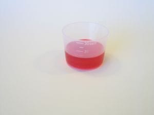 Children’s Cold Medicine Measuring Cup – Reckis v. Johnson & Johnson Case - Ferraro Law Firm Measuring cup filled with red liquid children’s cold medicine, connected to the Reckis v. Johnson & Johnson million lawsuit.