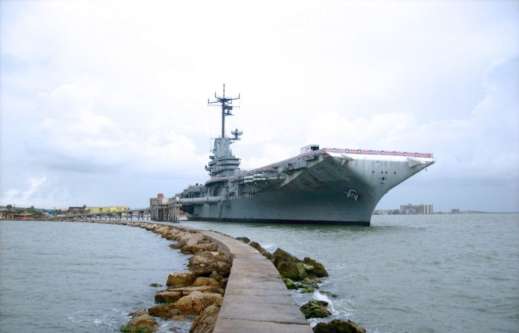 U.S. Navy Aircraft Carrier – Asbestos Exposure Risks - Ferraro Law Firm Large U.S. Navy aircraft carrier docked at port, symbolizing asbestos exposure risks for sailors and shipyard workers.