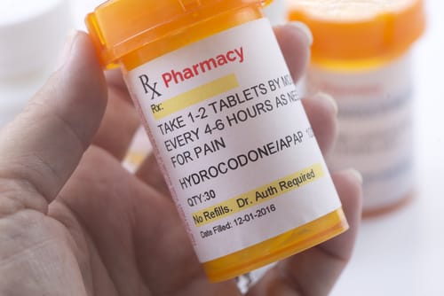 Prescription Bottle for Hydrocodone - Ferraro Law Firm Hand holding a prescription pill bottle labeled for hydrocodone, an opioid pain medication.