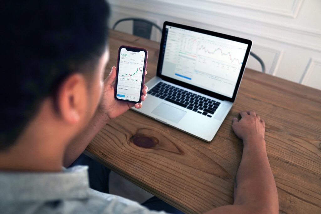 online investor checking investments on phone and laptop