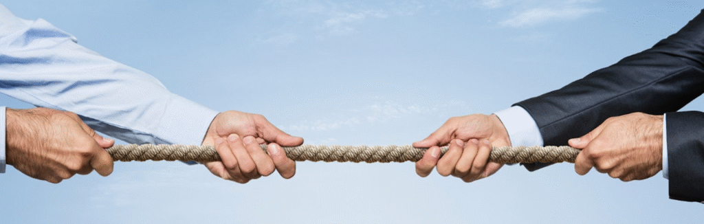 Close-up of two business professionals in suits and dress shirts engaged in a tug-of-war with a rope, symbolizing high-stakes commercial disputes.
