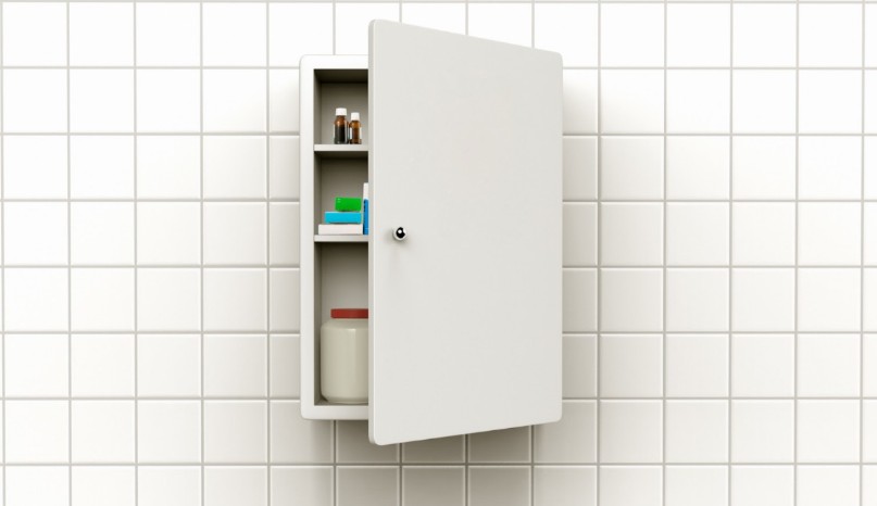 White bathroom medicine cabinet with shelves holding bottles, boxes, and a large talcum powder container.