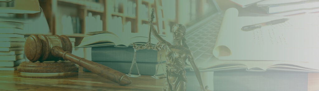 Gavel and scales of justice on a desk with law books and an open notebook nearby